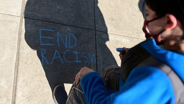 A child in Washington writes in chalk, "End racism," as people rally to protest recent violence against people of Asian descent March 21, 2021. (CNS photo/Erin Scott, Reuters)